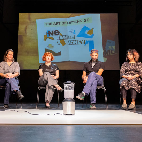 actors sitting in front of a mixer, in the background is a poster that reads "the art of letting go – no more white money"